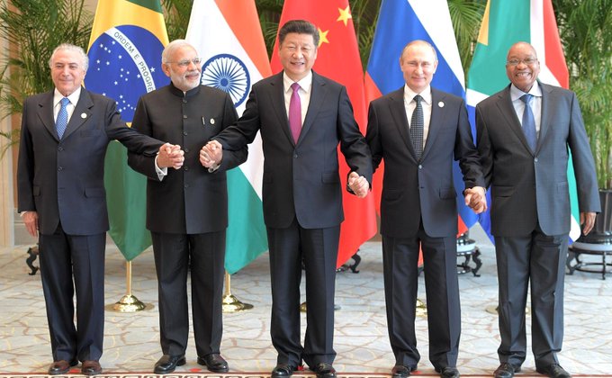 Leaders of BRICS nations, including Michel Temer of Brazil, Narendra Modi of India, Xi Jinping of China, Vladimir Putin of Russia, and Jacob Zuma of South Africa, hold hands, symbolizing cooperation as the nations discuss linking fast-payment systems and CBDCs.