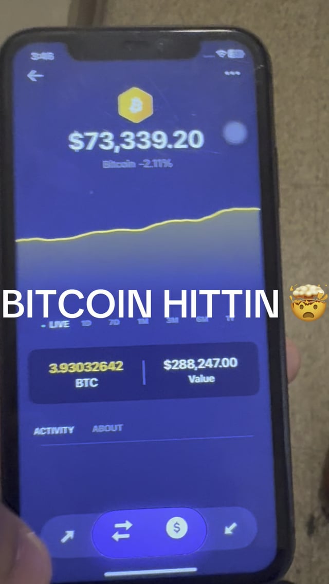 The image shows a person holding up a smartphone displaying a screen with a cryptocurrency chart, specifically focusing on Bitcoin trading. There are some words written across the display that might provide information about the Bitcoin price or the specific trade being executed. The photo seems unrelated to the main topic of the discussion and is just an interesting detail in this context.
