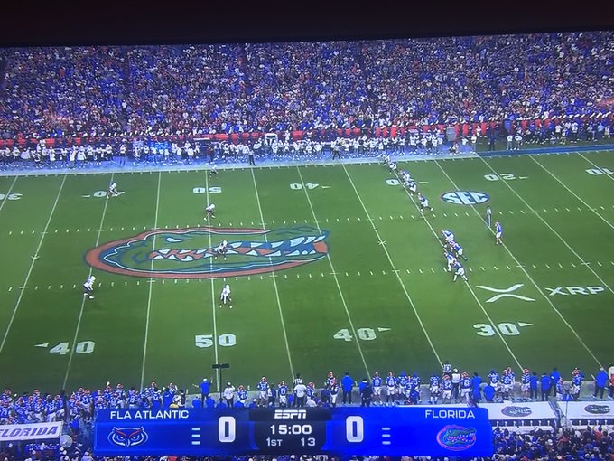 An SEC football matchup between Florida Atlantic and Florida is underway on ESPN, with the score tied 0-0 at 15:00 in the 1st quarter, while a prominent XRP logo is displayed on the field near the 30-yard line—tying into the post's excitement about XRP's visibility on the broadcast screen.