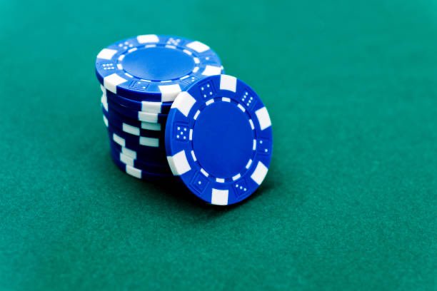 A small stack of blue and white poker chips resting on a green felt casino table surface.
