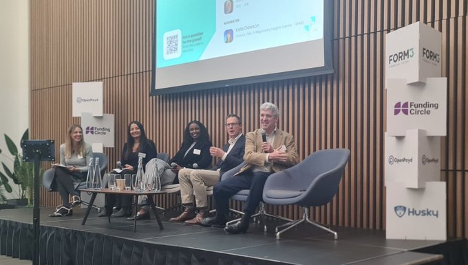 A panel discussion with five seated speakers on stage at an event featuring Funding Circle and OpenPayd branding, with stacked branded blocks on the side.