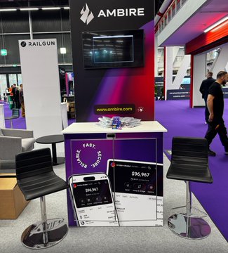 The image shows an indoor exhibition booth for Ambire & Railgun located inside a building with purple carpeting. The booth features two black chairs positioned next to each other, along with a table displaying some items such as cell phones and a sign that reads "There's a story behind Ambire & Railgun being side by side at @money2020". A person can be seen walking past the booth in the background.

The post on social media is likely promoting an event or product related to Ambire & Railgun, possibly showcasing their latest offerings or sharing interesting stories about the company's history and development.