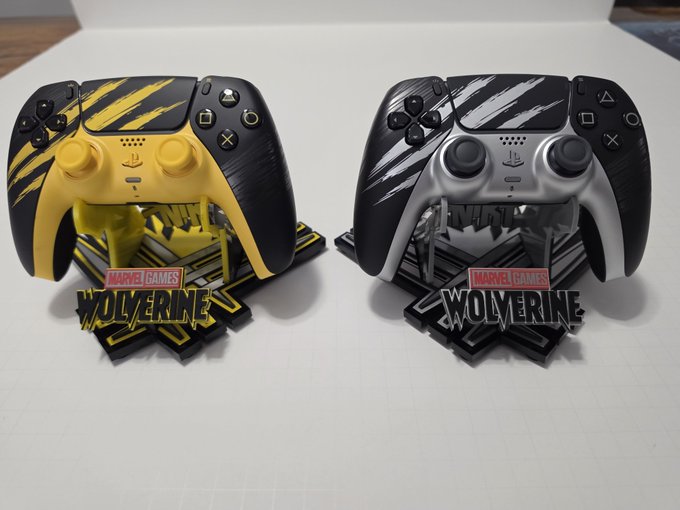 Two PlayStation 5 DualSense controllers displayed on stands themed after the Marvel game 'Wolverine' - one in yellow and black claw-mark design, the other in black and silver/white, each with a 'MARVEL GAMES WOLVERINE' logo base.