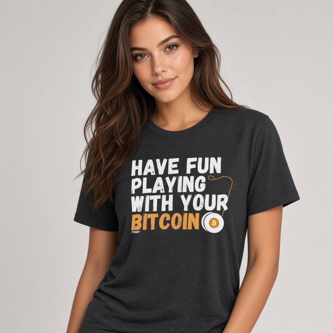 A product photo of a woman with long brown hair modeling a dark gray t-shirt that reads 'HAVE FUN PLAYING WITH YOUR BITCOIN' in white and orange text, with 'FUNCO' branding.