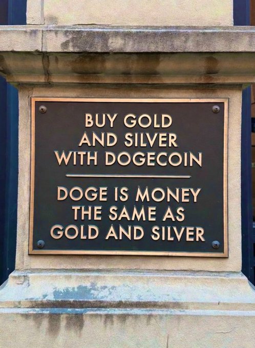A bronze plaque mounted on a stone wall that reads: 'BUY GOLD AND SILVER WITH DOGECOIN / DOGE IS MONEY THE SAME AS GOLD AND SILVER.'