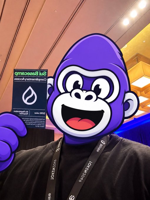 A person at what appears to be a crypto/Web3 conference with a purple gorilla emoji filter, holding a card for 'Coinmerce Börse Berlin' and wearing a 'LOYENSOMER' lanyard.