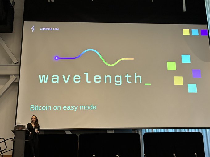 A presenter stands at a podium during a Wavelength workshop at TAB Conf, with a large screen displaying "wavelength_ Bitcoin on easy mode" alongside the Lightning Labs logo. The presentation aligns with the post's context of Lightning Labs (where roasbeef has built lnd since 2016) shifting its focus toward Ark as the future of Bitcoin.