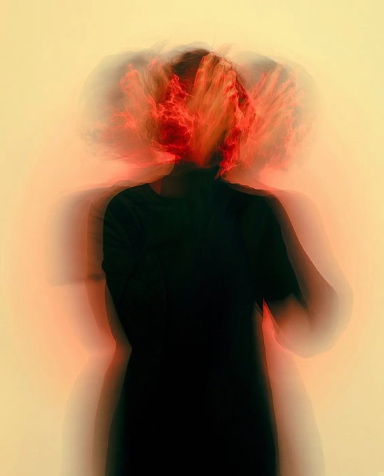 A blurred, artistic image of a person with vibrant orange and red hair against a yellow background.