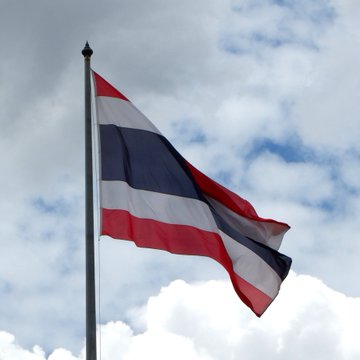 The flag of Thailand waves against a partly cloudy sky, symbolizing the nation's latest move to embrace cryptocurrency as it greenlights Bitcoin and Ethereum ETFs for trading in mid-October.