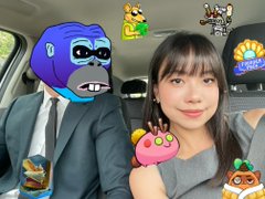 A woman takes a selfie in a car alongside an animated purple gorilla character wearing a suit, decorated with various cartoon stickers including Axie-style creatures, a flower, and a slice of cake. The post tags @AxieArtGallery and @RonkeOnRon, suggesting the image is a playful selfie tied to the Axie Infinity art community.