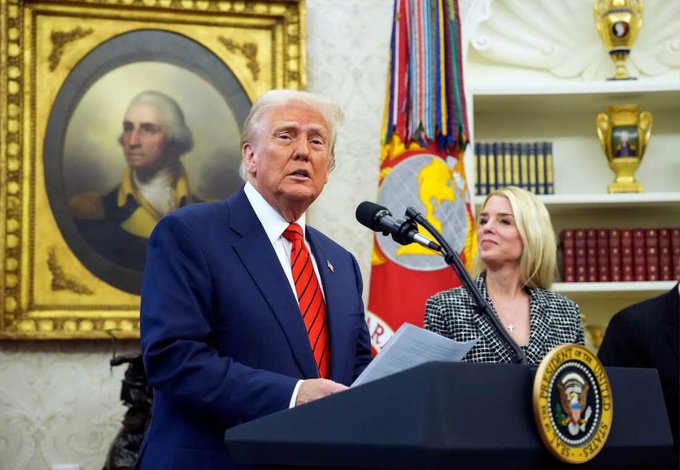 Donald Trump speaks at a podium showing the Presidential Seal, while a woman stands beside him, relevant to the news that the Trump DOJ will drop charges in a crypto Ponzi scheme.