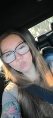 A selfie of a young woman with glasses and long brown hair in a car.
