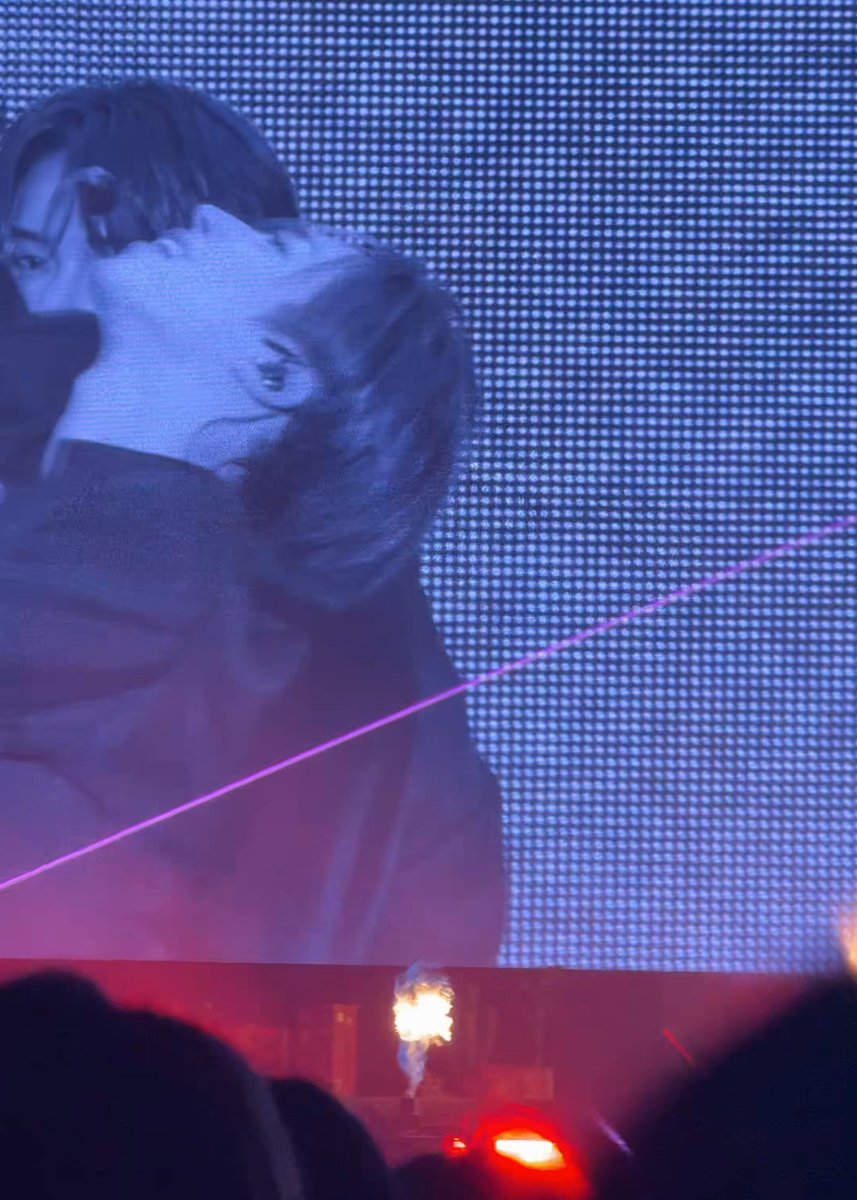 The image shows a large screen with a person's face, possibly a performer or an actor, displayed on it. The background of the image is blue, which contrasts with the white lines that are present on the screen. There are also some people in the scene who appear to be watching the performance. The post features a photo of a person and includes text such as "Hey Zhu Anxin #ANXIN #안신 #ALPHADRIVEONE #알파드라이브원".