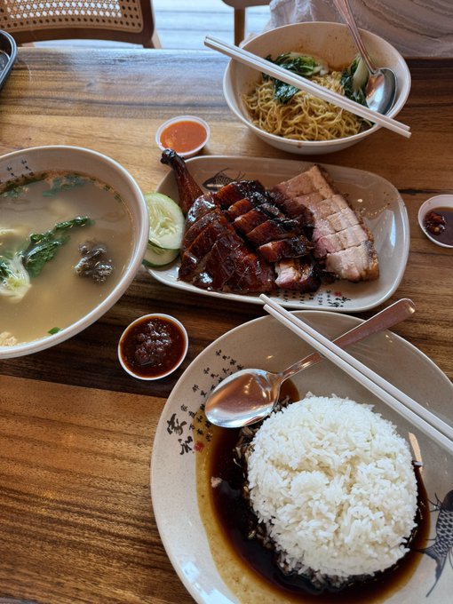 A traditional Hong Kong-style roast meat feast featuring glistening roasted duck, char siu, and crispy roasted pork served alongside noodles, rice with dark soy, and a clear broth soup. The spread showcases exactly the protein-heavy meal promised at 88 Hong Kong Roast Meat, with the signature trio of roasted meats plated together as the star of the meal.