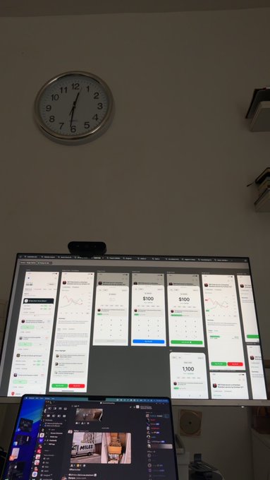 A wall-mounted analog clock shows approximately 6:28 above a monitor displaying multiple prediction market interfaces with $100 and $1,100 bet cards, alongside a laptop showing a Discord-like feed—visually representing the designer's mockup of a prediction market platform they built and want to showcase.