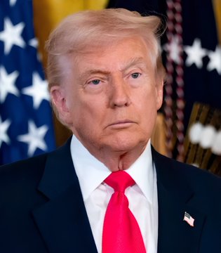 A portrait of Donald Trump wearing a dark suit and red tie, with an American flag visible in the background.
