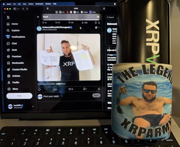The image features a laptop computer sitting next to a mug that has a picture of a man wearing swim trunks, holding a beer, with the text "THELEGEND" written above him. The mug also contains a photo of the man in the picture. The background of the image is black and white, but there are some texts visible on it as well. The laptop screen displays an image of another person wearing swim trunks and holding a beer.