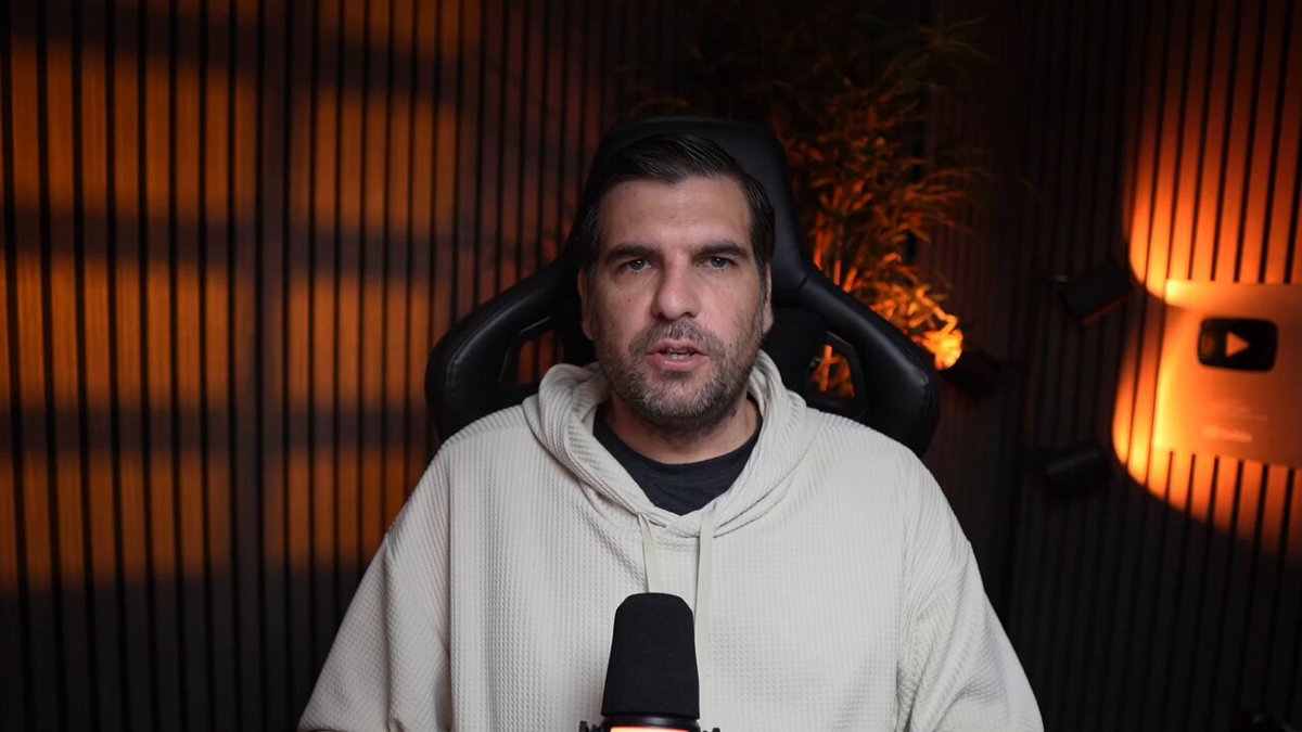 The image shows a man wearing a white hoodie sitting behind a microphone with his hands on his knees. The background features a wall with vertical stripes of varying shades of orange, creating an interesting visual effect that contrasts with the man's attire. The caption reads "You are missing the BIGGEST move in Cardano history You are missing the biggest move in Cardano history as a silent architectural shift permanently erases the friction blocking global enterprise adoption". This statement suggests that the man is talking about a significant event or development related to Bitcoin, possibly a historical moment when the cryptocurrency gained widespread acceptance and became an integral part of the financial landscape.

The image also contains some text elements such as "focus on what is in the image" and "behind closed doors", which could be related to the man's speech or the context surrounding his statement about Bitcoin.
