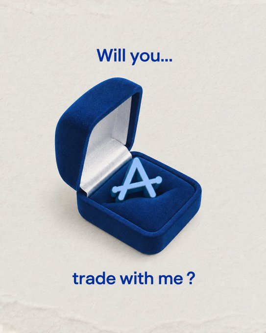 A blue velvet ring box holding an 'A' shaped ring with the text 'Will you... trade with me ?' displayed on a textured white background.