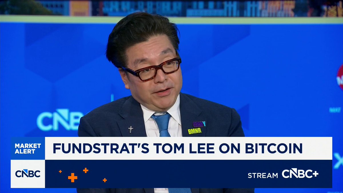 A CNBC "Market Alert" segment features Fundstrat's Tom Lee, identified by the chyron "FUNDSTRAT'S TOM LEE ON BITCOIN," speaking during an interview. He is well-dressed in a suit and tie with red glasses, with "GRY BMNR" pins on his lapel, illustrating the well-known commentator referenced in the post for his many colorful bullish expressions.