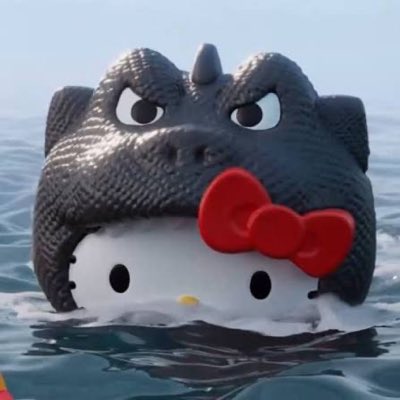 The image features a Hello Kitty character wearing a Godzilla costume helmet while floating in water, directly tying into the advertised $GodKitty coin launch on 8/18 at 8:00pm EST celebrating the new Hello Kitty and Godzilla collaboration.
