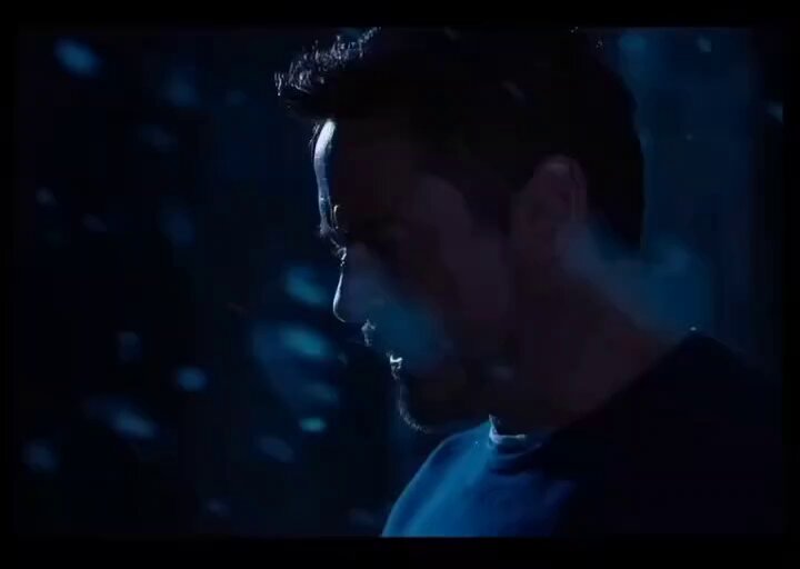 The image shows a man with a beard wearing a blue shirt, looking down at his phone screen. The background of the image is dark and blurry, creating an atmosphere of mystery or intrigue. The caption below the image reads "When you finally hit 7 figures and your laptop won'n turn on. It made me who i am." This phrase seems to be related to a character from the movie Iron Man, suggesting that the man in the image might have encountered a similar situation with his phone.