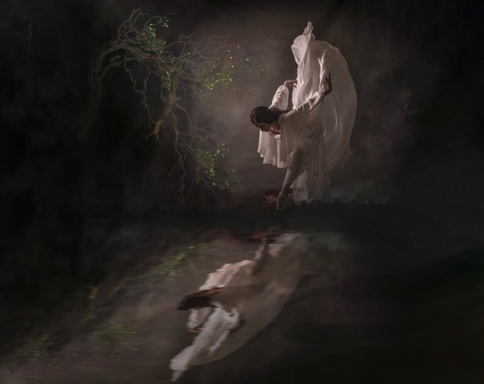 A dark, moody fine art photograph shows a ballerina in a flowing white dress posed dramatically beside a tree, reflected in water below.
