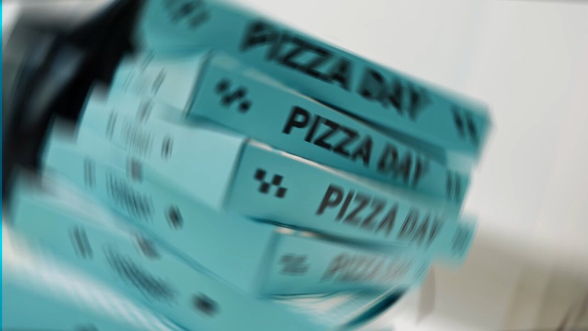The image features a stack of blue boxes with the words "Pizza Day" written on them, suggesting that they are promotional items for an event or product related to pizza. The boxes appear to be slightly tilted, giving the impression that they have been tossed around in the wind. The text "Boxed For Opportunities!" is also present, which could indicate a partnership between the company and someone named Bitget.