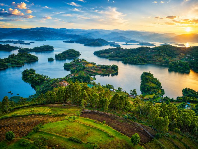 The image shows a beautiful landscape with several lakes surrounded by mountains. The sun is setting behind these mountains, creating a stunning backdrop for the scene. The sky above the water is filled with clouds, adding depth and texture to the view. The overall atmosphere of the photo conveys a sense of tranquility and peace as it captures the beauty of nature at dusk.