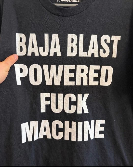 A black t-shirt with bold white text reading 'BAJA BLAST POWERED FUCK MACHINE', branded with 'mioossprints' at the collar.