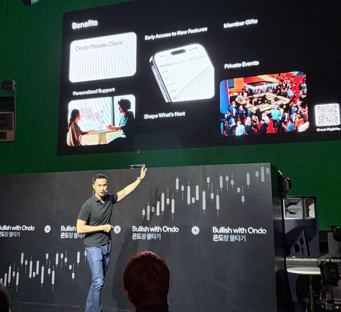 A presenter on stage at a 'Bullish with Ondo' (온도랑 풀다) event gestures toward a large screen displaying membership benefits including Ondo Private Client, Early Access, Member Gifts, Private Events, and Personalized Support.