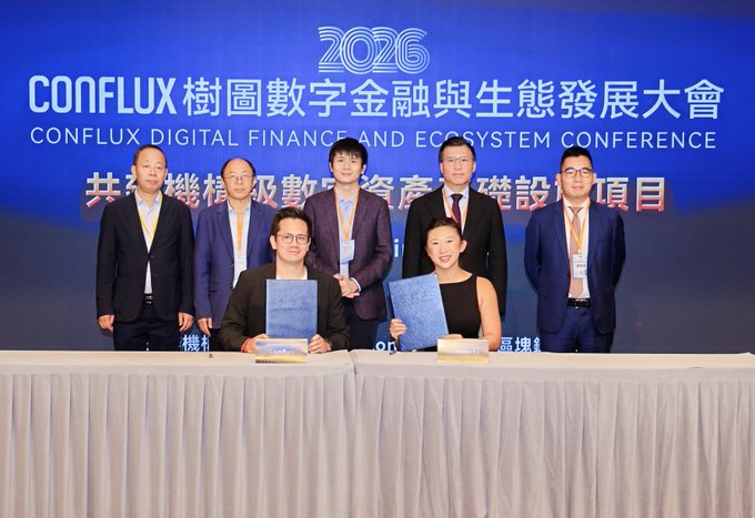 The image shows a group of people standing behind a table with a blue banner that says "Conflux Digital Finance & Econosystem Conference" written on it. The people are posing for a photo, and there are two men sitting at the table signing papers in front of them. One man is holding a book while they sign the documents.