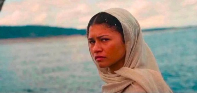 A woman in a beige headscarf stands by the ocean with a skeptical, judgmental expression. The image humorously captures the awkward, unimpressed reaction someone might give on a first date when hearing an unsolicited pitch about XRP's bridge currency solution.