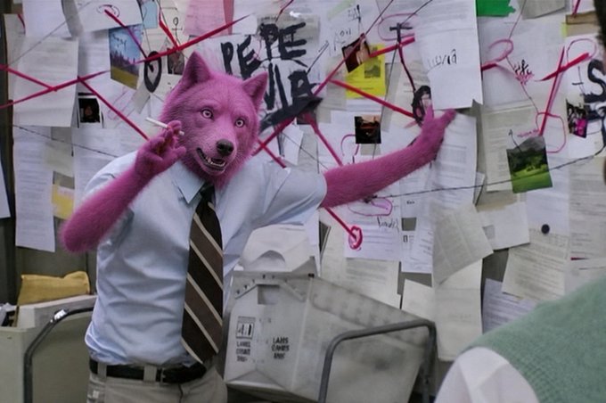 A person in a light blue shirt and striped tie wears a bright pink wolf mask while gesturing emphatically in front of a wall covered in papers, scribbles, and red connecting strings, with the name "PEPE" scrawled above. The chaotic conspiracy-board aesthetic humorously illustrates the post's joke about trying to untangle the complex mechanics of $PACK.