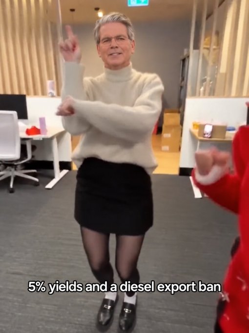 A person in an office setting wears a cream sweater, black skirt, and heels, pointing upward with text reading "5% yields and a diesel export ban".