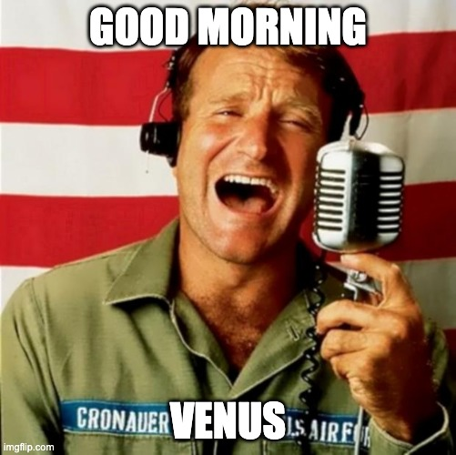 A still of Adrian Cronauer (Robin Williams) from Good Morning, Vietnam, wearing headphones and shouting into a microphone in front of an American flag, with "GOOD MORNING" at the top and "CRONAUER VENUS" patched on his shirt. The patched text humorously edits his name tag from "Airborne" to "Venus," pairing with the "gm, just Venus" caption as a punny morning greeting.
