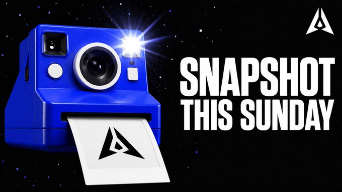 A blue Polaroid-style instant camera with its flash glowing prints a photo bearing a triangular logo, set against a starry black background, alongside bold text reading "SNAPSHOT THIS SUNDAY" with the same triangular logo in the corner, visually reinforcing the announcement of GenLayer's upcoming points snapshot.