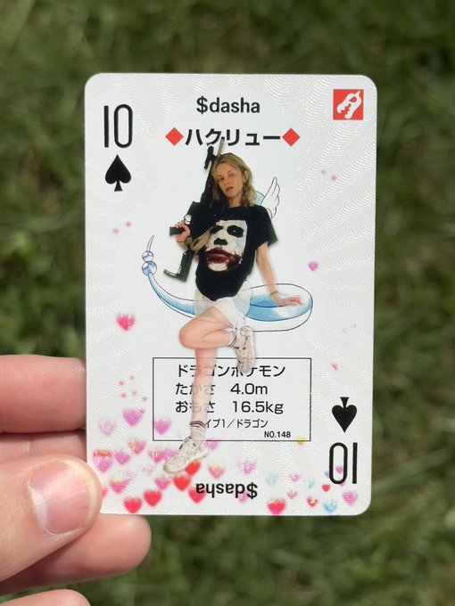 A hand holds a custom Pokémon-style playing card labeled "$dasha" featuring a 10 of spades, with a photo of a person seated in a bathtub holding a rifle, styled as a Haunter (No. 148) at 16.5kg and 4.0m tall. The card's playful design merges meme culture with Pokémon card aesthetics, branding the subject as a fierce "Dragon/Ghost" type.