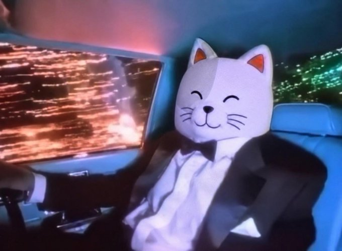 An animated scene depicts a person wearing a smiling white cat mask and a black tuxedo, sitting inside a car with neon city lights visible through the windows.
