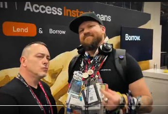 Two men stand at an "Access Insta-Loans" booth featuring "Lend & Borrow" signage at what appears to be a convention or trade show. The scene humorously juxtaposes the post's claim about being in a "music video with Miss America," suggesting the image is likely a screenshot from that comedic video.