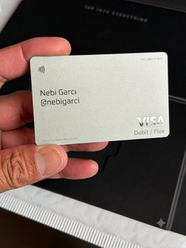 A hand holds a metal Visa debit card branded "Nebi Garci / @nebigarci," presented as a sleek, personalized crypto-style card resting on a dark box. The image showcases a fintech debit card design, illustrating the type of product Xmoney could potentially bring to Turkey.