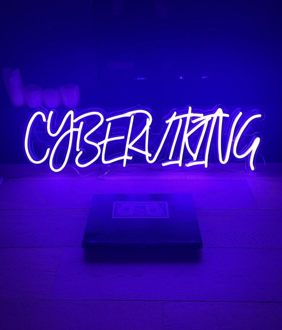 A neon-style sign reading 'CYBER ASTRO' in white outline lettering glows with purple/blue ambient light, sitting on a wooden surface above a black base unit with three circular controls.