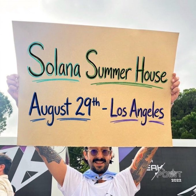 A smiling man with tattoos and sunglasses holds up a cardboard sign reading 'Solana Summer House, August 29th - Los Angeles' at an outdoor event.
