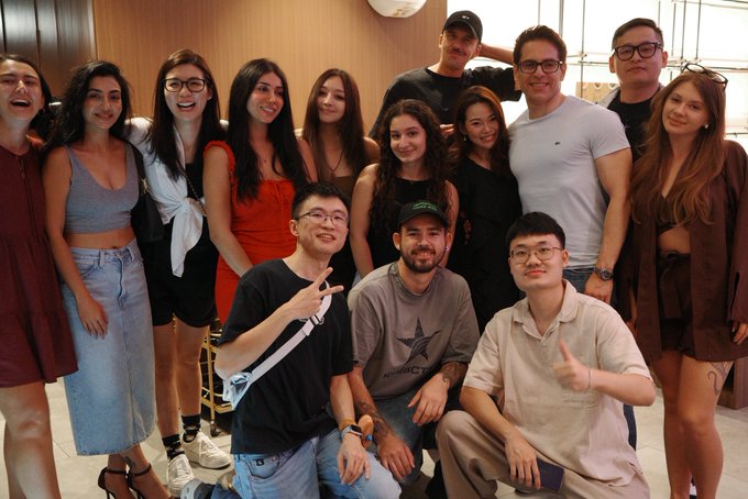 A group of people smile and pose for the camera at what appears to be an indoor gathering.