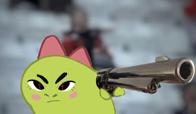 The image features a green monster with red eyes holding a gun, giving off an angry or aggressive vibe. The monster appears to be pointing the gun at someone, possibly another character from the post. The background of the image shows a blurred crowd, suggesting that this scene takes place in a public setting like a stadium or event venue.