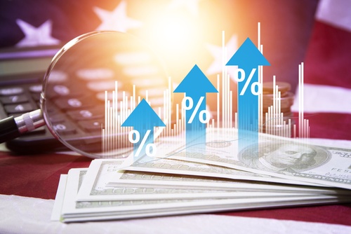 A financial-themed image showing US dollar bills, coins, a calculator, and a magnifying glass overlaid with blue upward arrows and percentage signs against an American flag background.