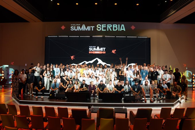 A large group photo of attendees at the 'SOURIA SUMMIT SERBIA' event, posed together on a stage with the summit logo displayed on screens behind them.