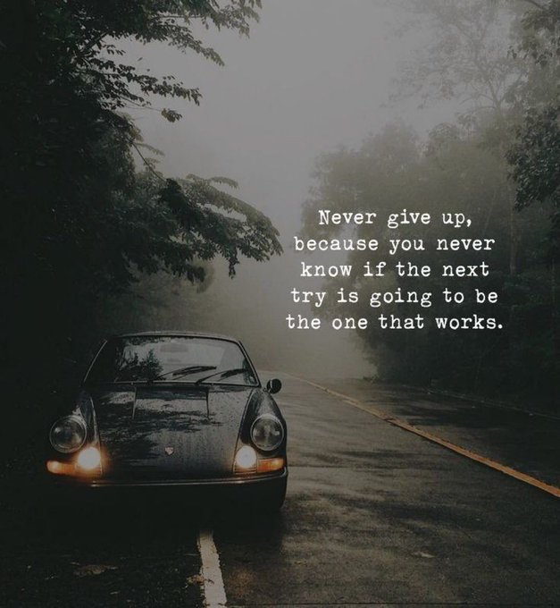 A moody photo of a dark sports car with headlights on, parked on a foggy forest road, overlaid with the text: "Never give up, because you never know if the next try is going to be the one that works."