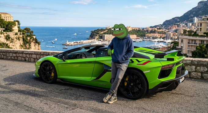 A person wearing a Pepe the Frog mask and blue hoodie leans against a bright green sports car parked on a coastal road overlooking a harbor and Mediterranean town.