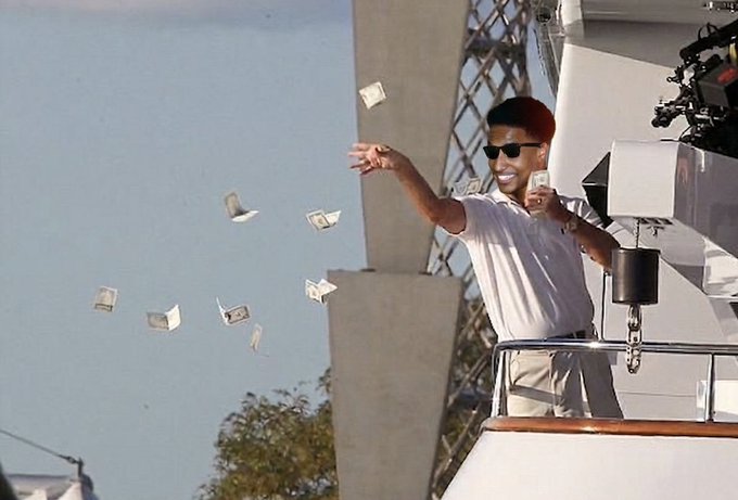 A still from a movie showing a smiling man in a white polo shirt and sunglasses throwing money in the air from a boat.